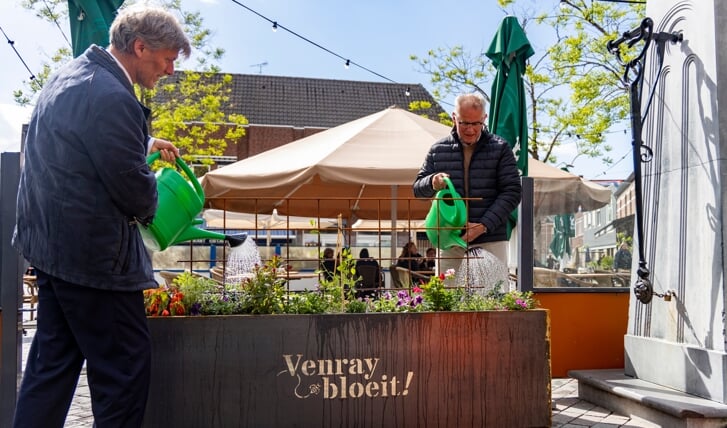 Wethouder Jan Loonen (links) en initiatiefnemer Antoon Verlinden verrichten de symbolische openingshandeling bij de waterpomp op de Grote Markt in in Venray.