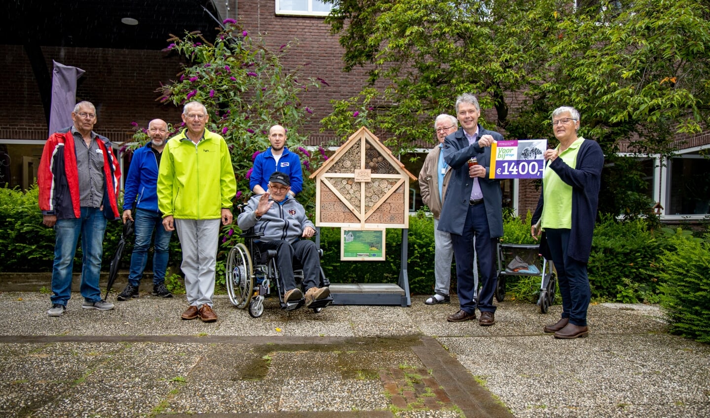 Bewoners van Rooyhof, vertegenwoordigers van stichting Ik Begin en IVN Geijsteren-Venray en oud-burgemeester Hans Gilissen bij het bijenhotel.