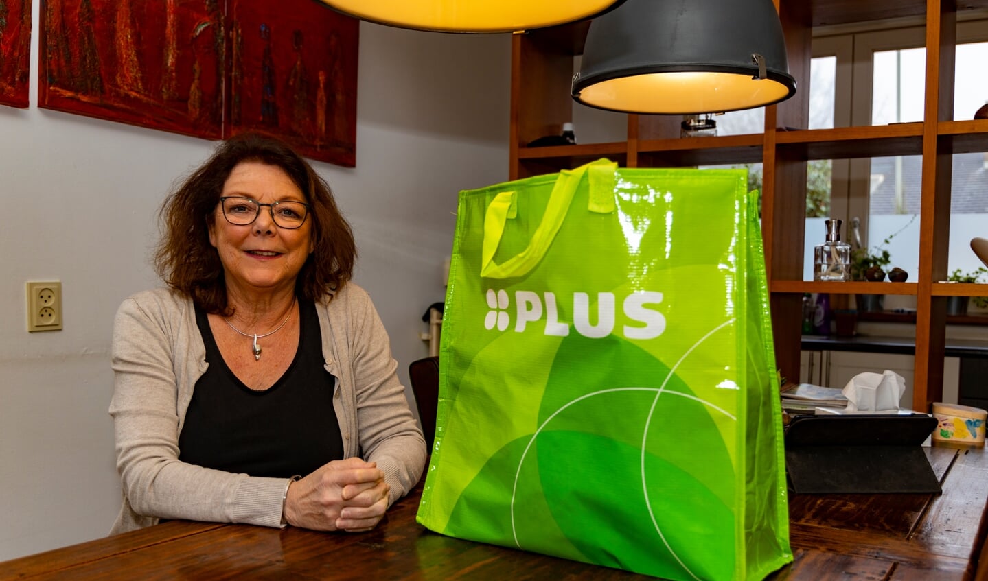 Elly Alkemade neemt haar levensmiddelenpakket van PLUS Guido van Dijck in ontvangst.