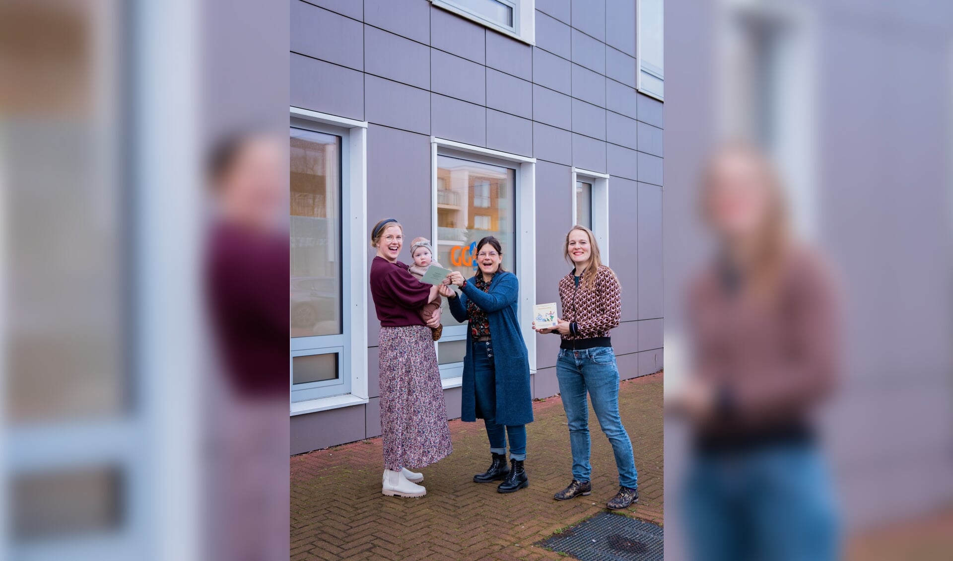 Teuntje Smits met haar dochter Bobbie (links) neemt de eerste beweegbundel in ontvangst uit handen van JGZ-verpleegkundige Mariëlle Hagens (midden) en Floor Kooijman van Kinderfysiotherapie Venray (rechts). 