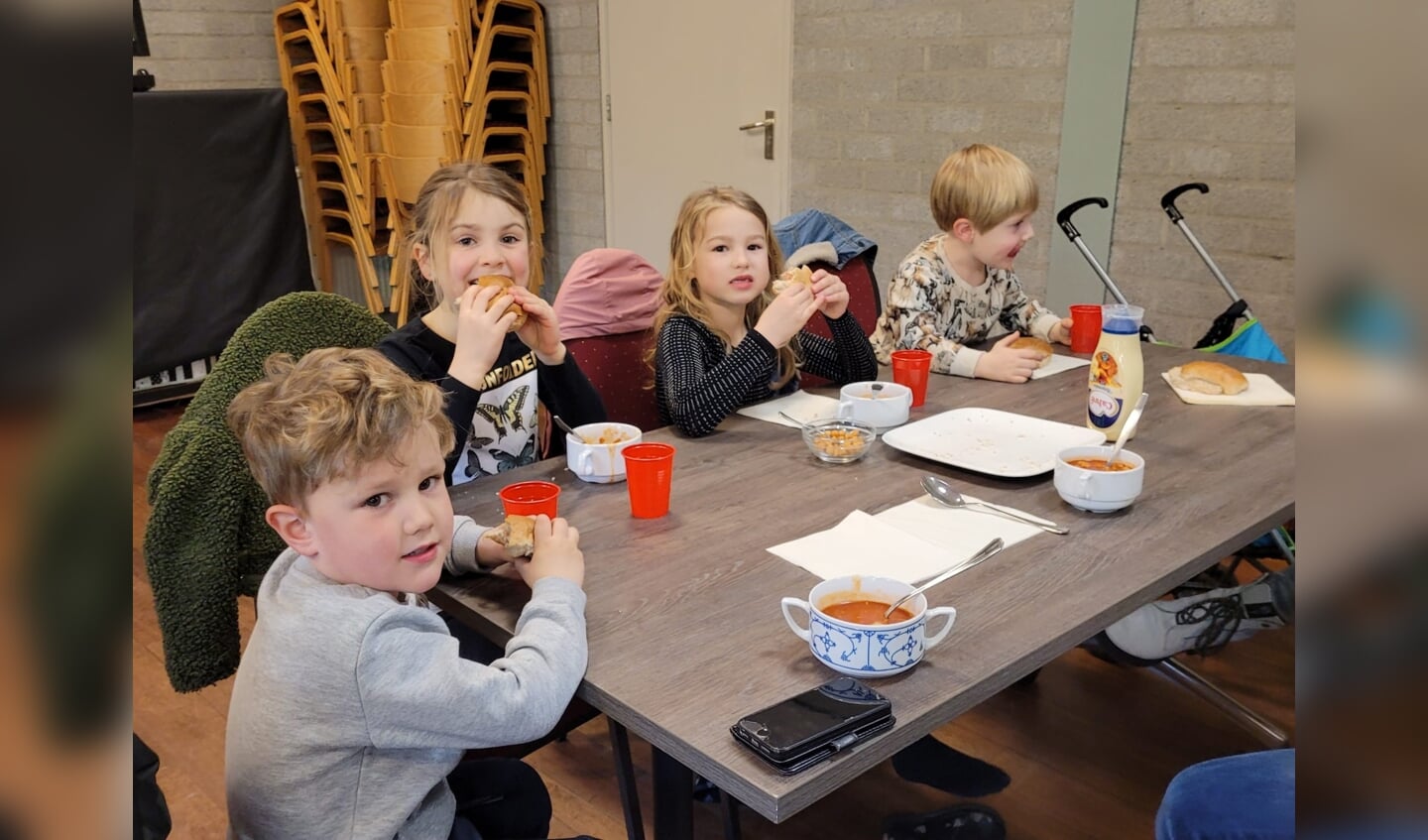 Vier jonge zwerfafvalopruimers genieten van soep en een broodje. 