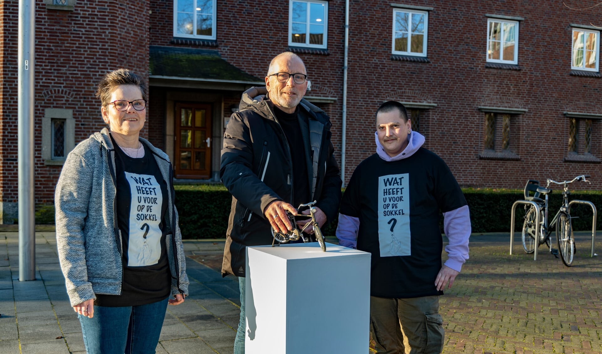Wethouder Erik van Daal (midden) plaatste een fiets op de sokkel en vertelde zijn verhaal aan de wijkbewoners Willeke Heldens (links) en Sam van de Vorle. 