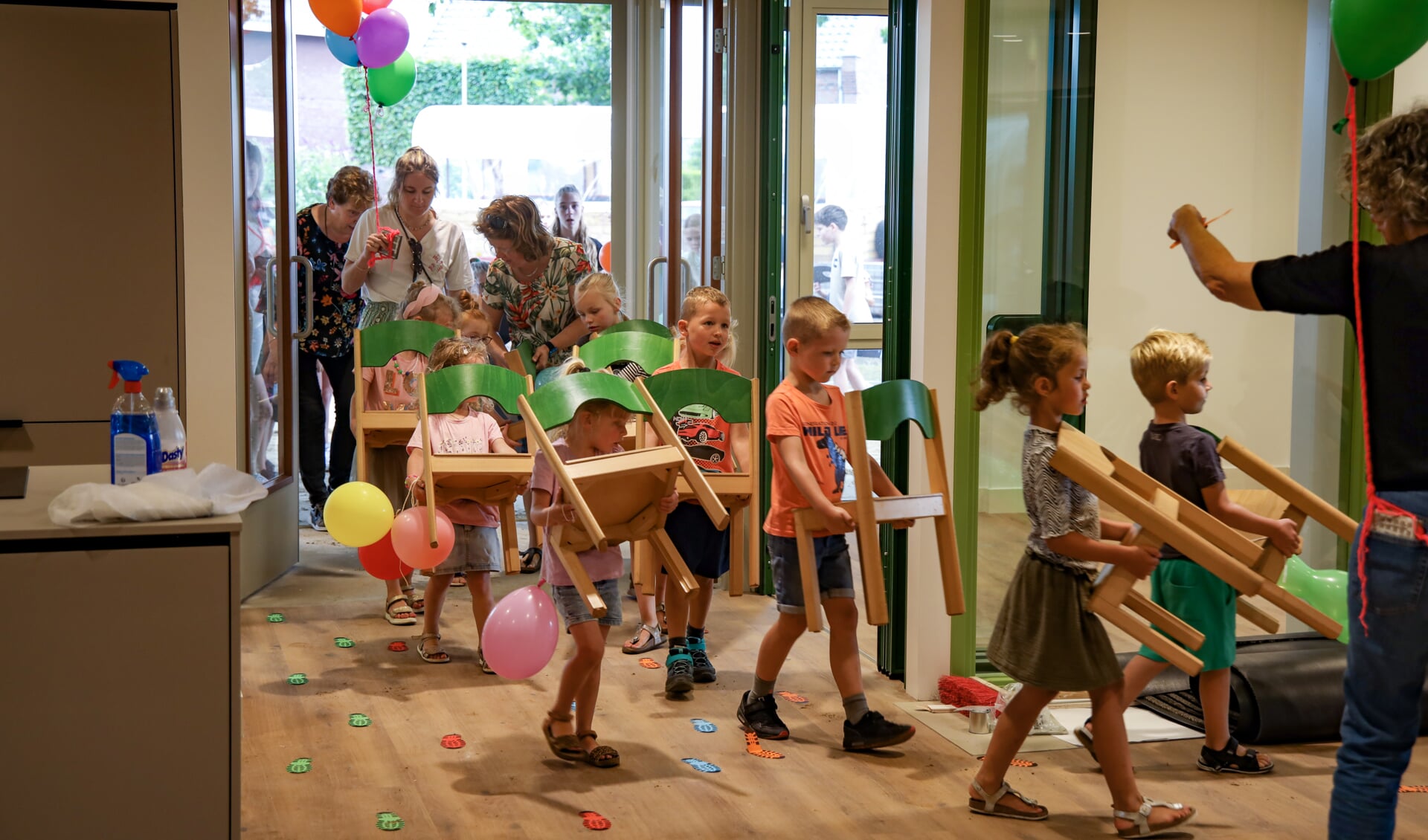 De leerlingen van De Lier in Merselo dragen elk hun eigen stoel het nieuwe schoolgebouw binnen. 