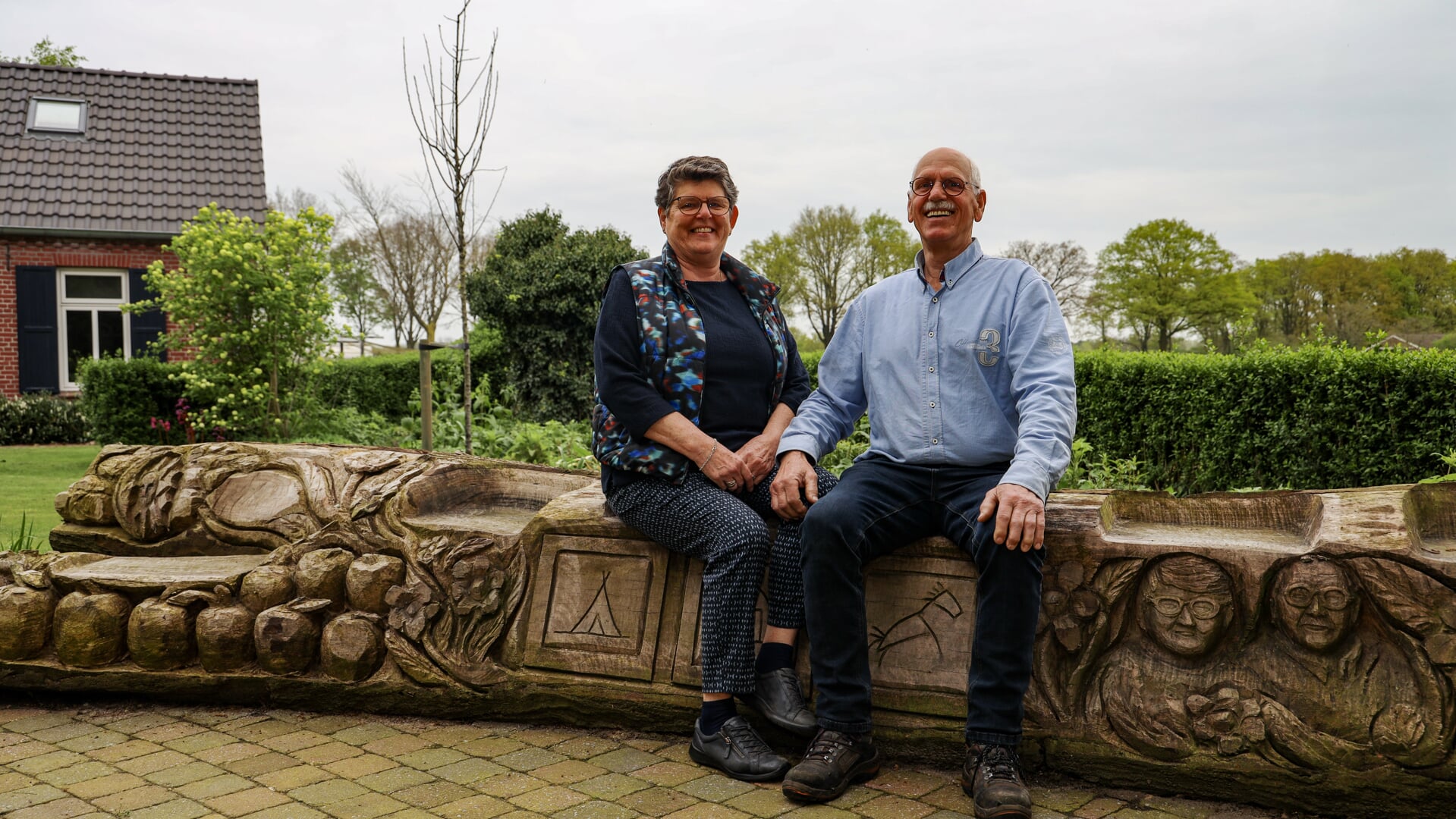 Gerrie en Jan van der Haghen op de tot kunstwerk gemaakte stam van de boom die ze vijftig jaar geleden hebben geplant.