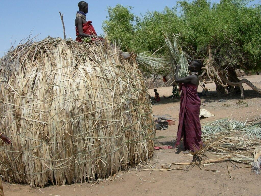 Bewoners bouwen een hut van lokaal materiaal.