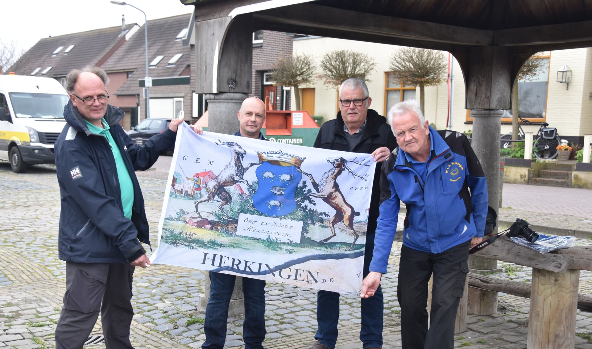 Leden van de Dorpsraad Herkingen, André van Beek en Adri Knöps (links en rechts in het midden) presenteren de nieuwe Herkingse vlag. Links Wim van Schilfgaarden van de Jachthaven en rechts Ad Zegers van de Watersportvereniging.