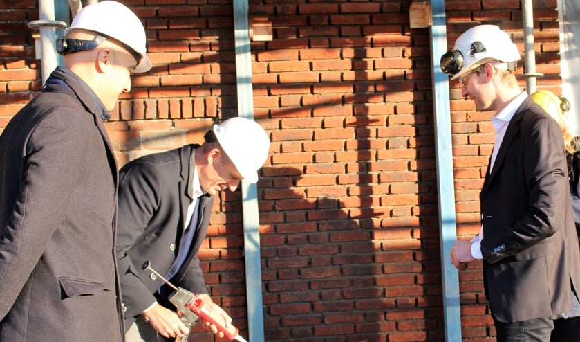 Markwat en Frank Oudenes, projectleider De Langen en Van den Berg, plaatsen de steen.