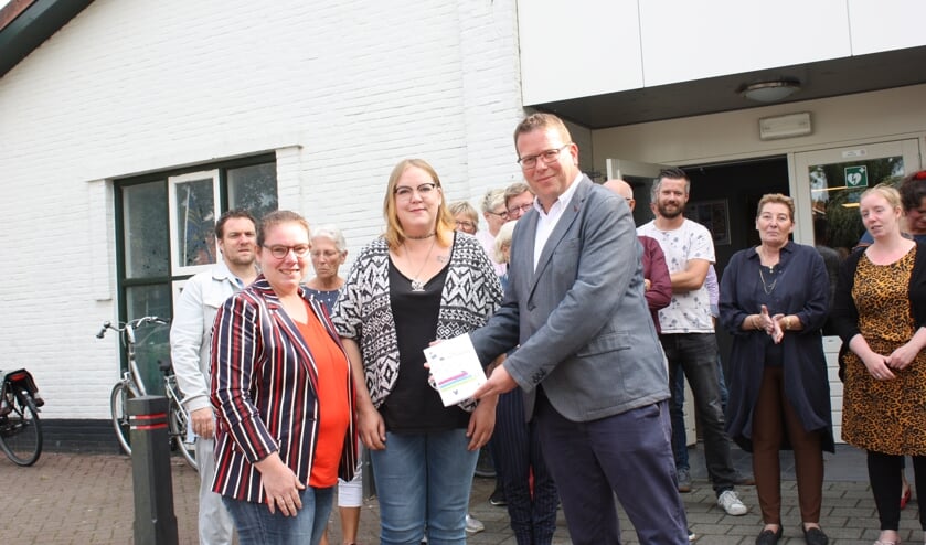 Wethouder Bruggeman neemt het bundeltje columns in ontvangst. Links Nicole Gierman, midden Laura van Helden.
