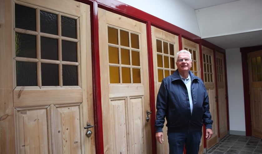 Jaap van Nieuwenhuijzen in de gang van de school van zijn jeugd. Links de toiletten.