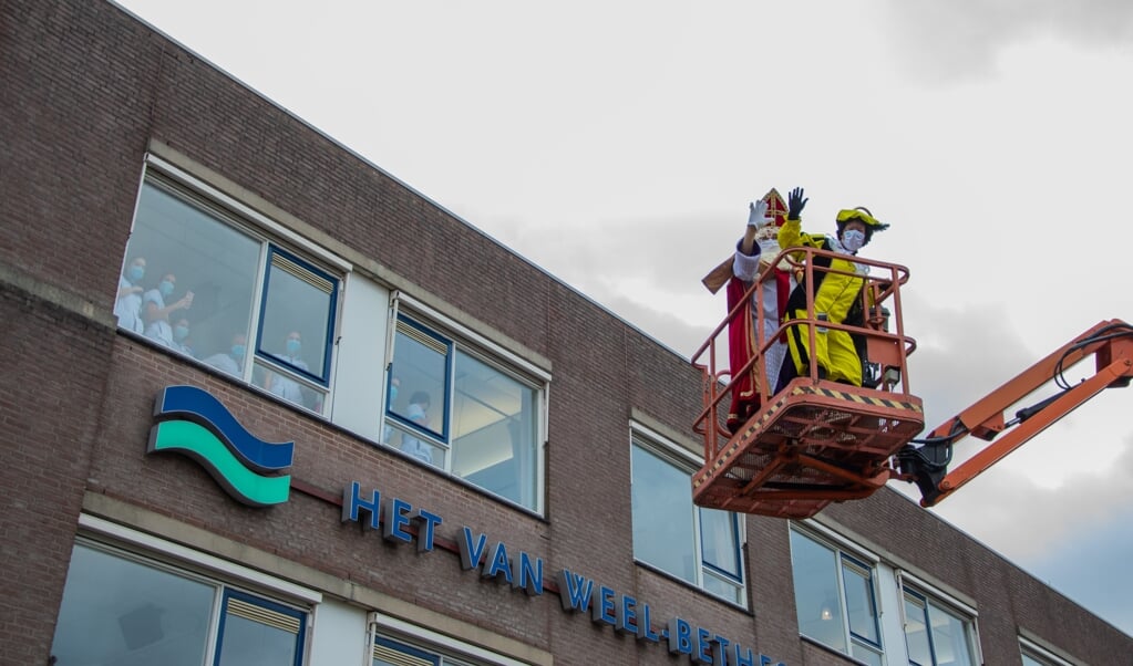 Het wiebelde flink, maar Sint en Piet deden het toch maar: zwaaien naar de patiënten vanuit een hoogwerker (Foto: Sam Fish).