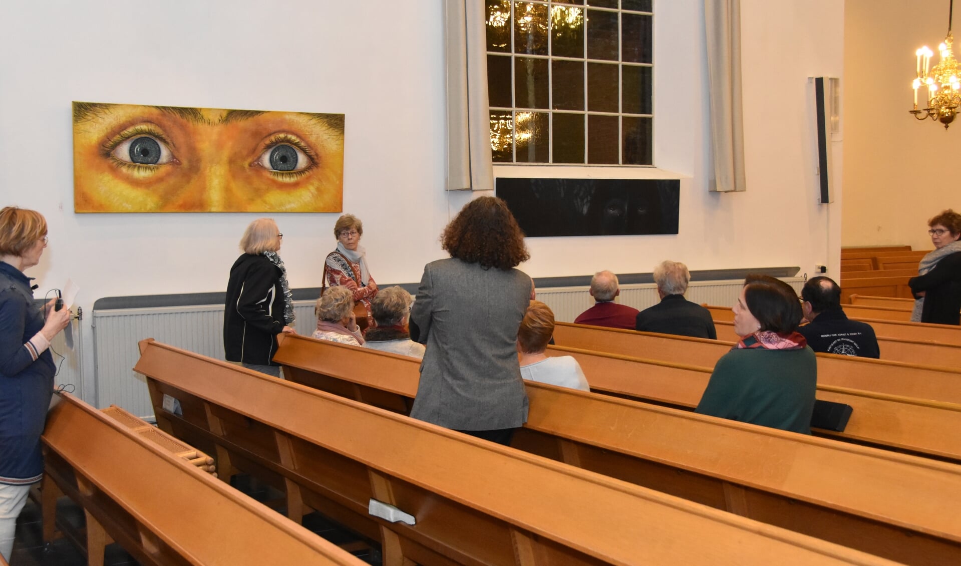 Marijke Snoek (links) geeft uitleg bij haar schilderijen in de kerk.
