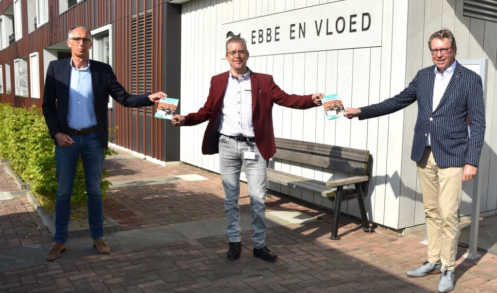 Op gepaste afstand overhandigen Jan Verhage (rechts) en Flip Bokelaar (links) een puzzelboekje aan Jan Looij. De boekjes worden verspreid over de verschillende vestigingen van CuraMare.