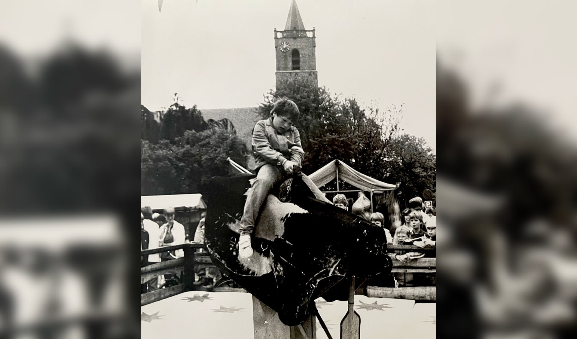 Richard Groenendijk als kind op de rodeostier, op de achtergrond de kerktoren van Dirksland met de klok links op de toren. Daar zit de klok ook vandaag de dag nog (Foto: privéarchief Richard Groenendijk).