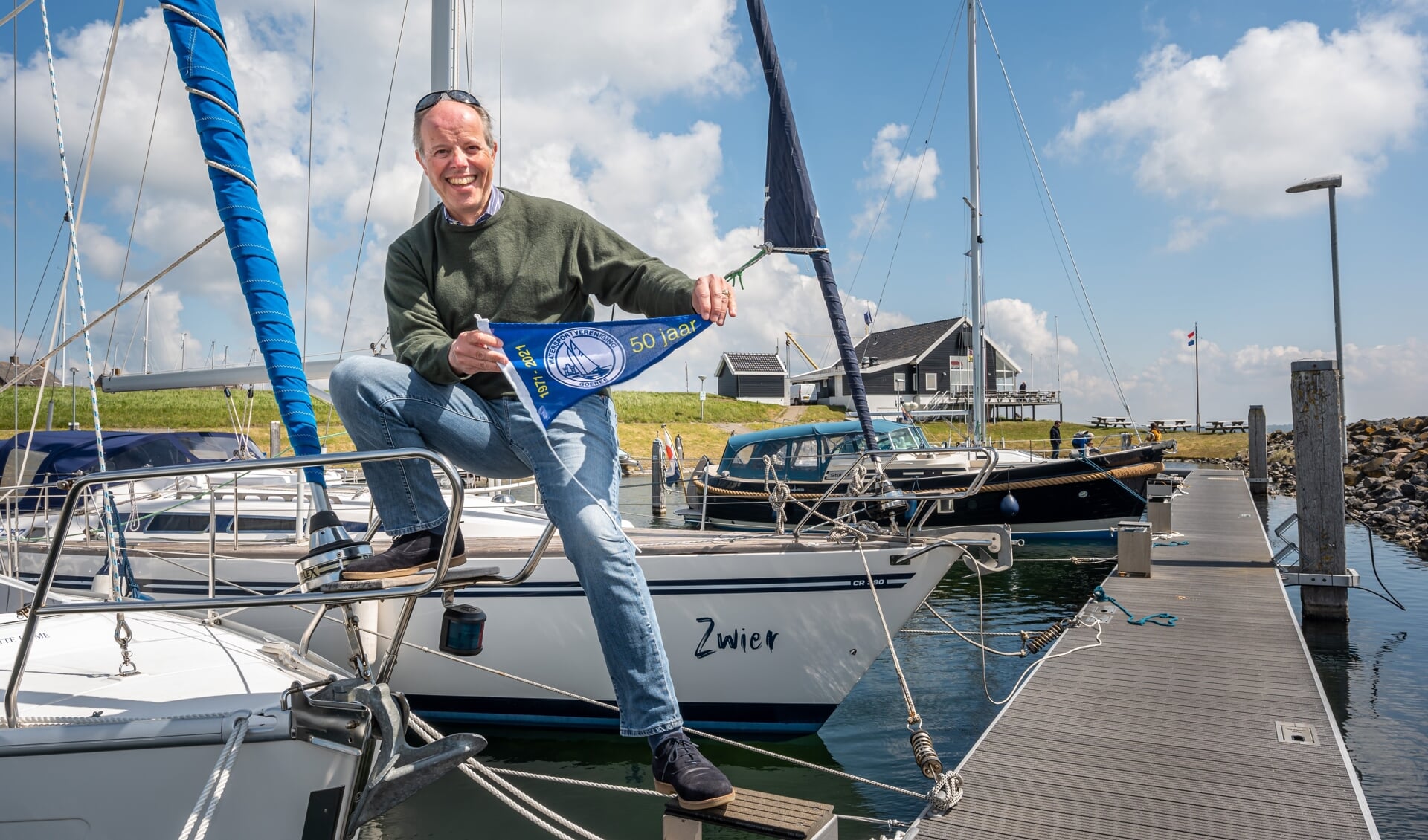 Voorzitter Frederik van der Dussen van WSV Goeree met het jubileumvlaggetje in de Ouddorpse haven (Foto: Wim van Vossen).