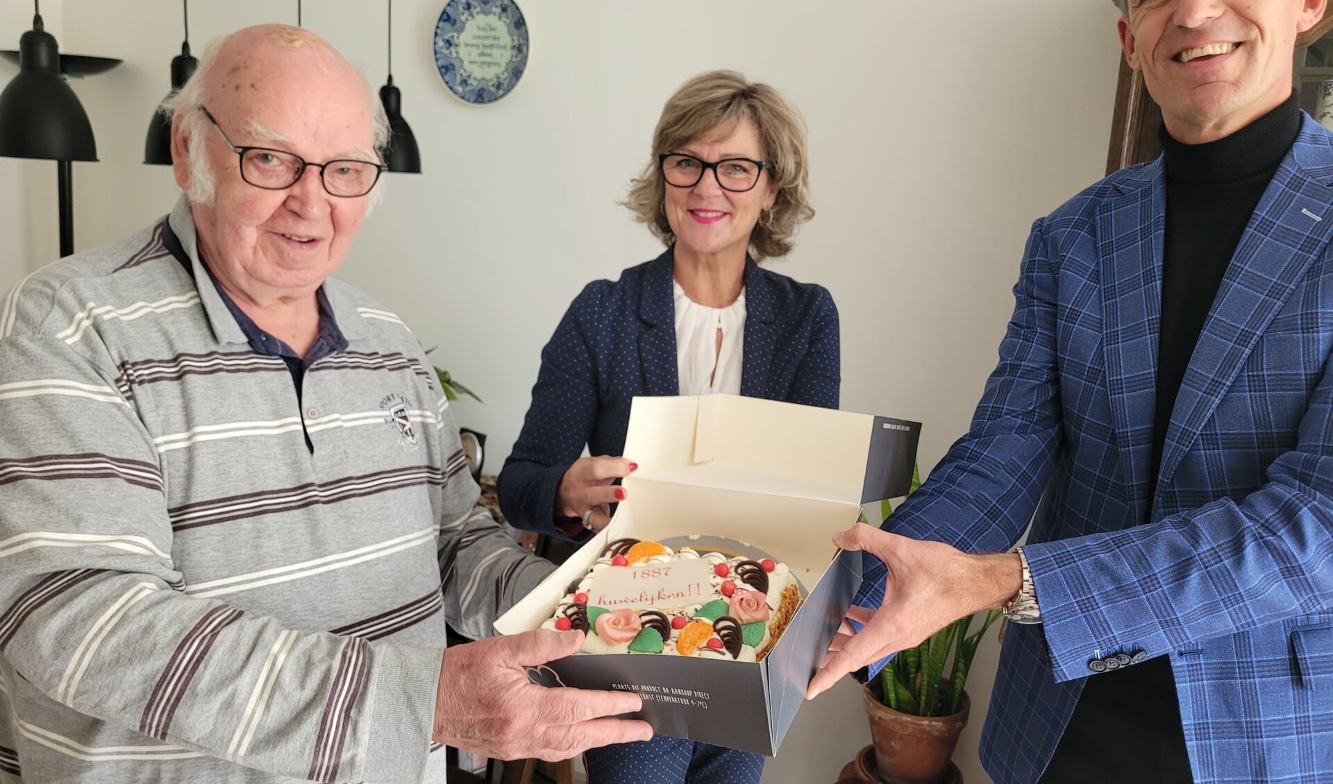 Klaas Baas kreeg taart uit handen van de burgemeester en de wethouder (Foto: gemeente Goeree-Overflakkee).