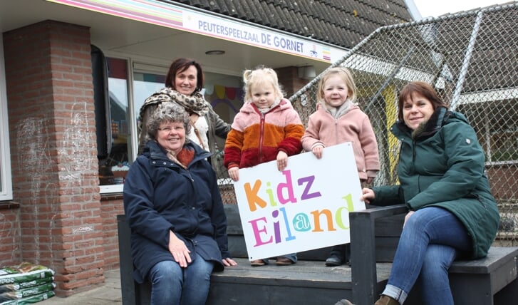 V.l.n.r. directeur-bestuurder Anne Verhey en de pedagogisch medewerkers Coby Nolet en Marga van Opijnen, rond de kinderen die het logo van Stichting Kidzeiland presenteren.