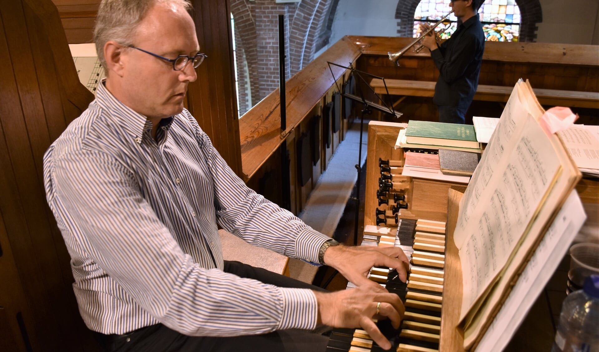 De twee muzikale liefdes van Ron Braber in een beeld gevangen: het bespelen van het orgel en de trompet.
