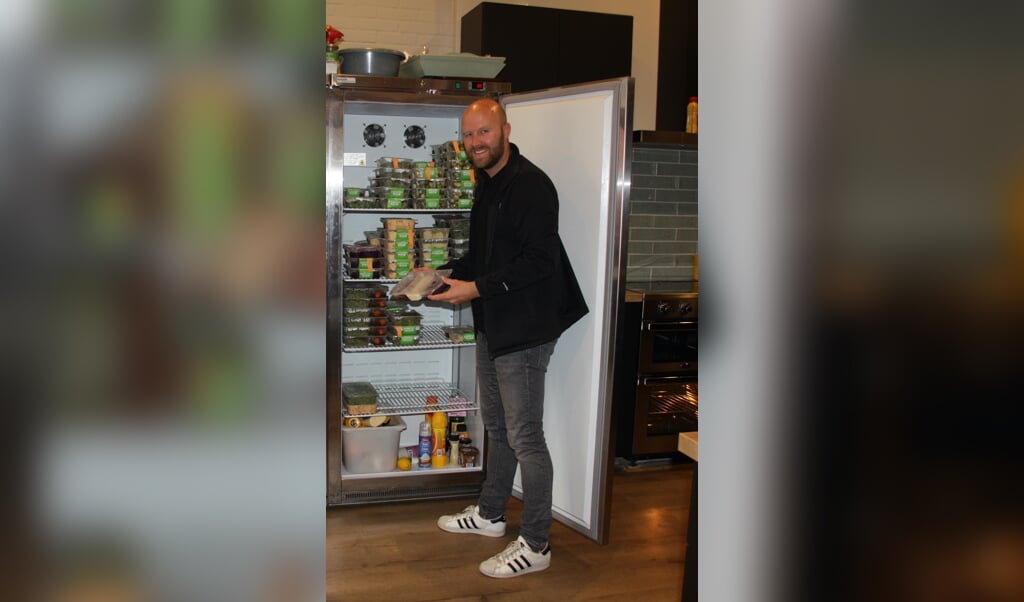 Dennis Maliepaard, vrijwilliger bij Stichting de Eetkamer laat de maaltijden zien, die klaarliggen in de koelkast.