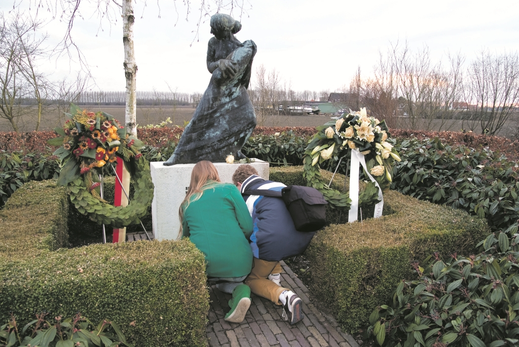 Twee leerlingen uit Veenendaal geknield bij het monument, om er een bloemstuk neer te leggen. Foto: Hans Villerius