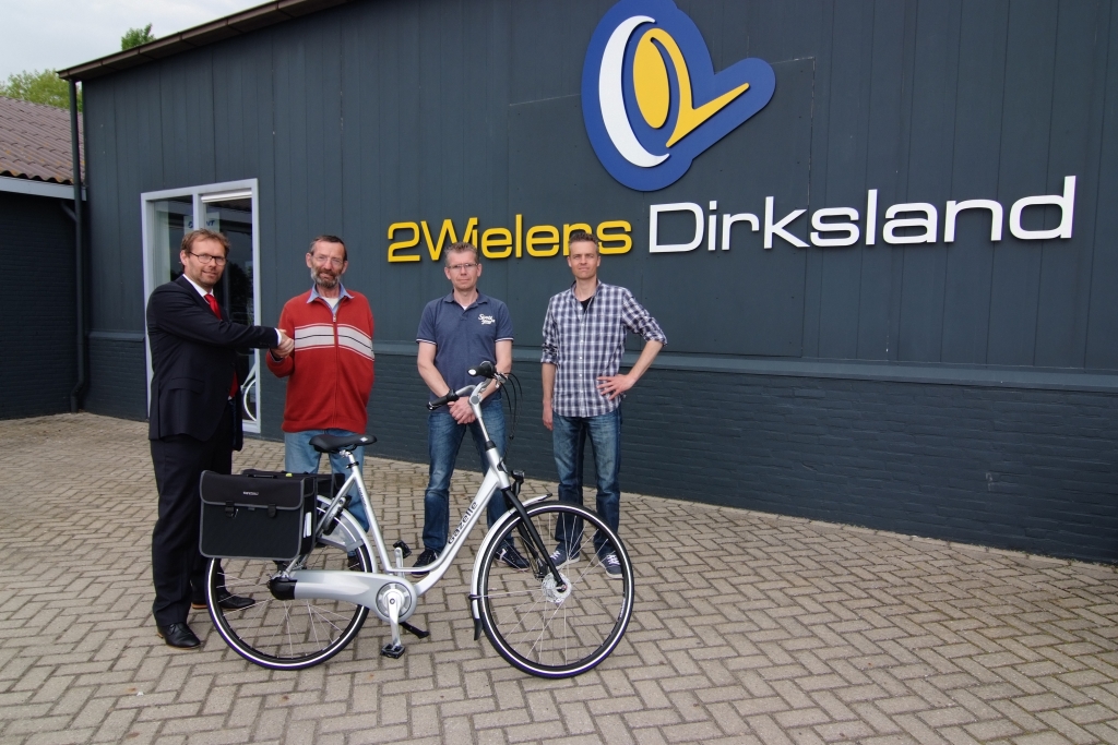 Hans Teunis van ENRA (links) overhandigt de fiets aan Dimmen Borgdorff. Rechts staan André van 't Hof en Elwin van Groningen van 2Wielers Dirksland.