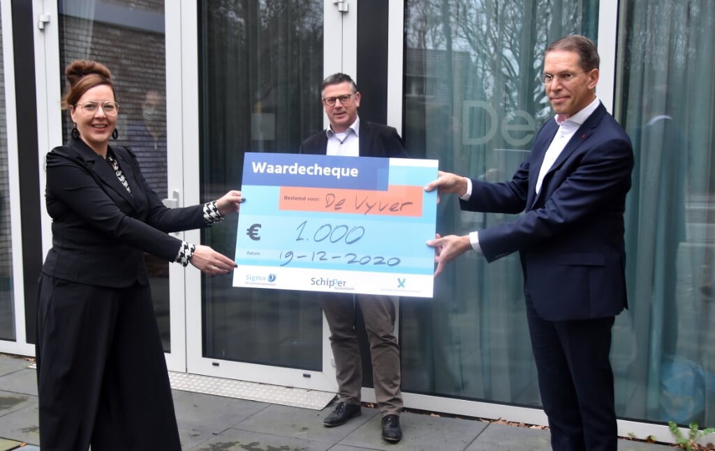 André Bruggeman (rechts) overhandigt de cheque aan Corrie de Boed van De Vyver. In het midden Jaap van Oostenbrugge, voorzitter van Stichting Vrienden van Sjaloom.