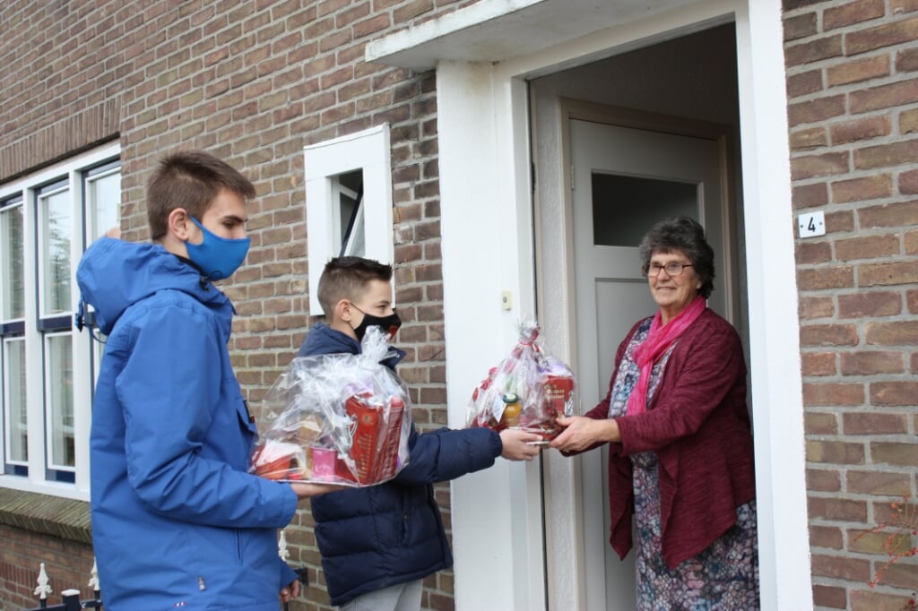 Jan de Bruin en Tom Visbeen overhandigen een pakket aan een inwoonster van Melissant.