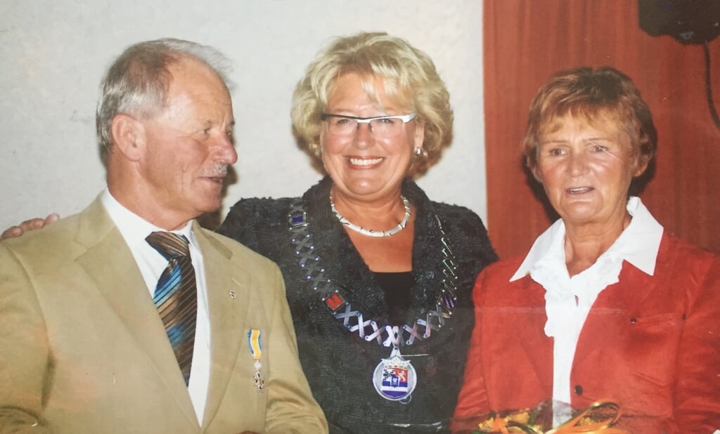 Lau Almekinders (l) kreeg in 2008 in het bijzijn van zijn vrouw Adrie (r) de koninklijke onderscheiding opgespeld door burgemeester Hommes (m).