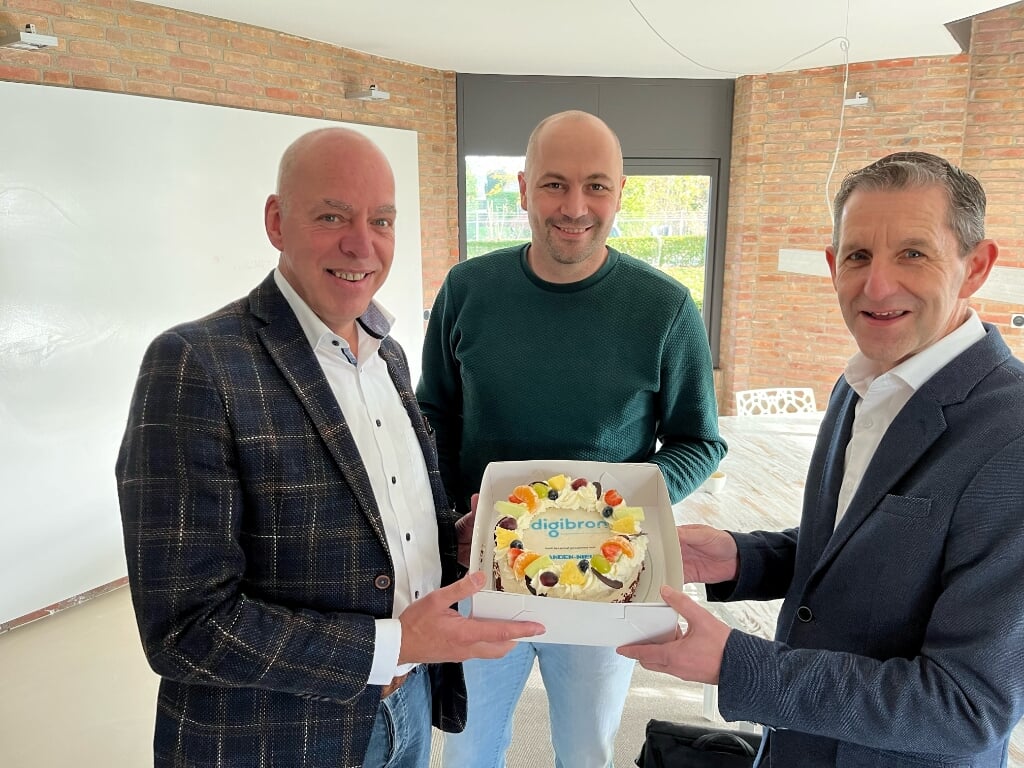 V.l.n.r. Ab van der Veer (directeur) en Gert Klok (hoofdredacteur) van Eilanden-Nieuws ontvangen uit handen van Bart van Dam een taart namens Digibron. 