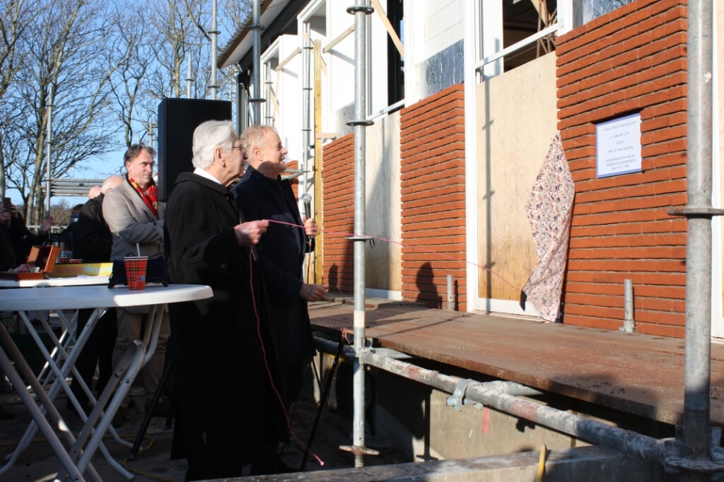 Oud-burgemeester Van Velzen trekt aan een touwtje en onthult daarmee de eerste steen (Foto: Kees van Rixoort).