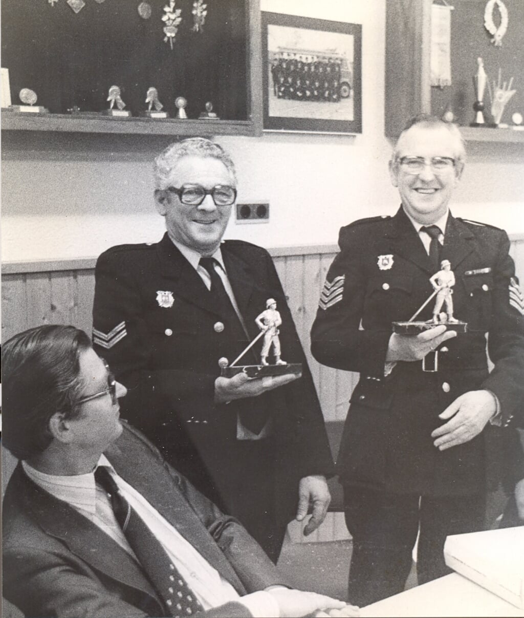 De heren C. Moerkerke (l.) en W. Ras (r.) met de zilveren brandweerman. Links en vooraan burg. v. Velzen van Goedereede.