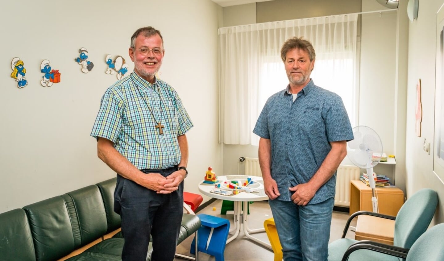 Pastor Jan Lange en Luc Zandstra, hoofd van bibliotheek, onderwijs en sport (rechts), gaan over de Ouder-Kindprojecten in PI Alphen. Zij poseren in de familiekamer van de gevangenis. 