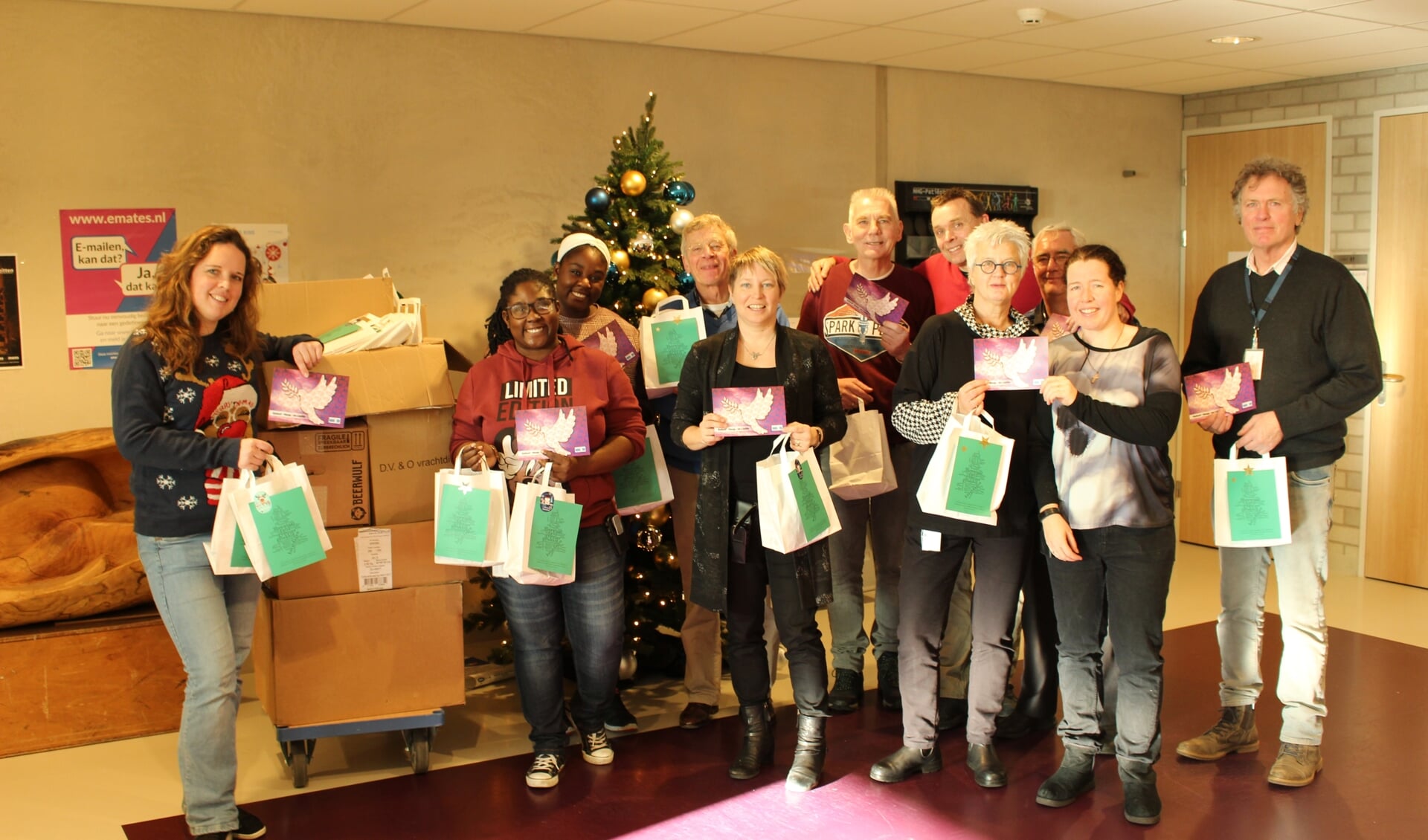 Vrijwilligers DSG De Sluis en medewerkers Geestelijke Verzorging JCZ Zaanstad delen attenties uit. Links de kar met de 850 pakketjes.