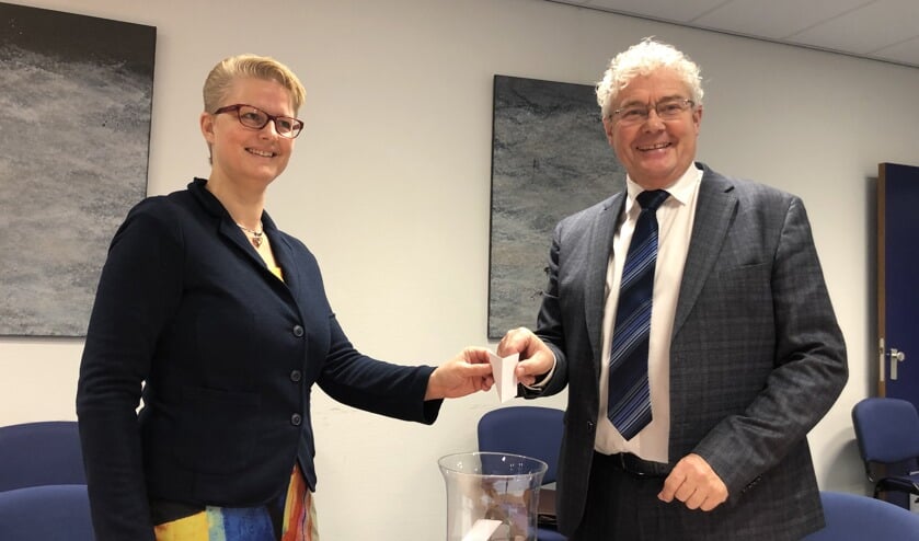 Notaris Van Nimwegen (l) overhandigt de lijst met geselecteerde woningen aan wethouder Houtenbos.