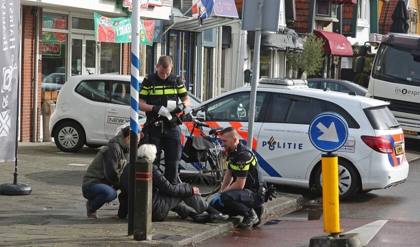 Agenten en een omstander verlenen de vrouw na de valpartij eerste hulp.