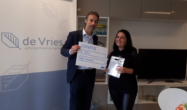 Linda neemt de cheque voor Stichting Bal Anand in ontvangst.