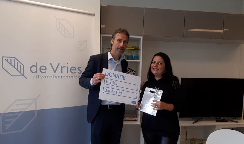 Linda neemt de cheque voor Stichting Bal Anand in ontvangst.