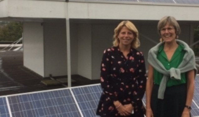 Zonnepanelen op het dak van het gemeentehuis. Mandy Elfferich en Jacobien van Beijen laten zien dat de gemeente zelf ook meedoet.