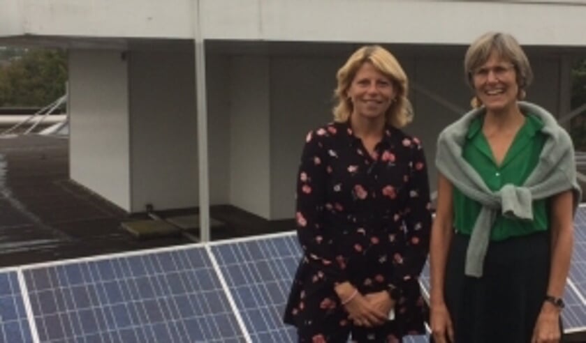 Zonnepanelen op het dak van het gemeentehuis. Mandy Elfferich en Jacobien van Beijen laten zien dat de gemeente zelf ook meedoet.