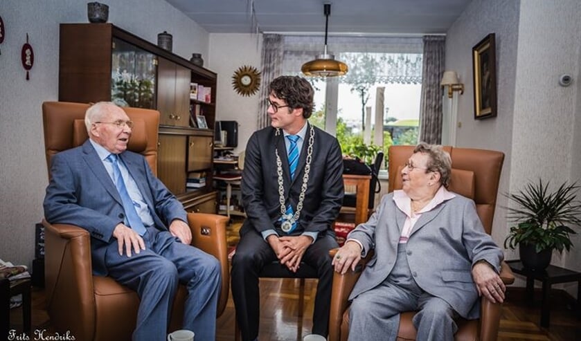 De heer en mevrouw Hendriks krijgen bezoek van loco-burgemeester Merijn Snoek.