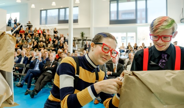 Scholieren verrichten, met de onthulling van een aantal fotokunstwerken, de officiële opening van de vernieuwde school.