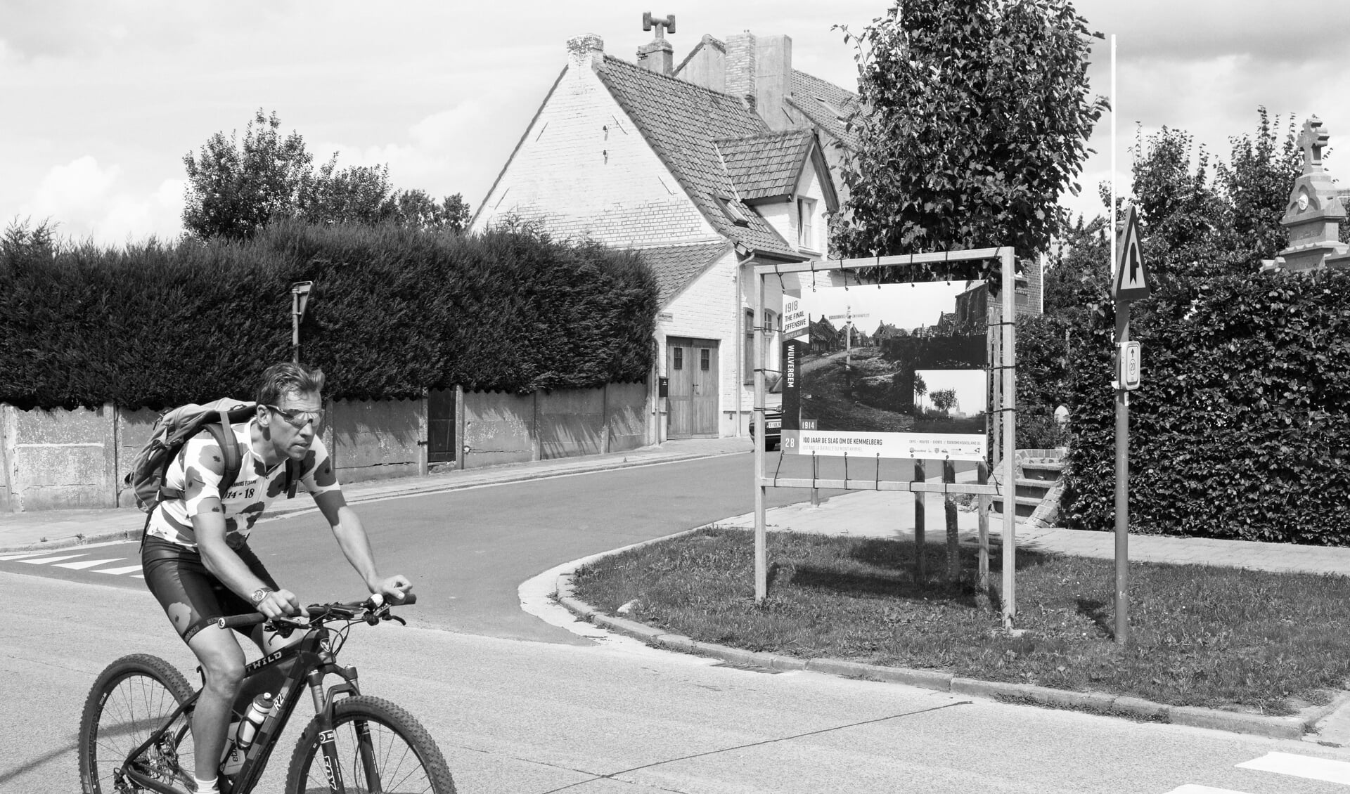 Wulvergem in de Belgische Westhoek. De man op de fiets draagt een shirt met klaprozen. De klaproos staat in Groot-Brittannië symbool voor de Eerste Wereldoorlog. Op het billboard wordt aandacht besteed aan 100 jaar Slag om de Kemmelberg