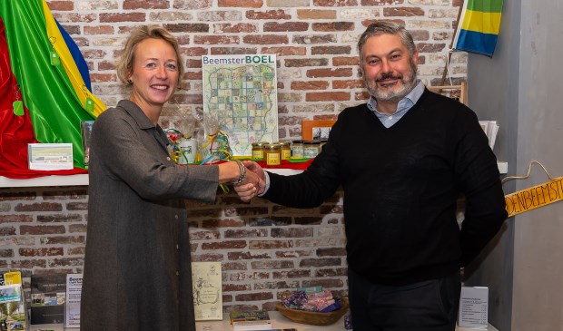 Daniëlle Woudstra en Moncef Beekhof bezegelen de samenwerking. Op de achtergrond de producten uit Beemster die nu een prominente plek hebben in de VVV-winkel.