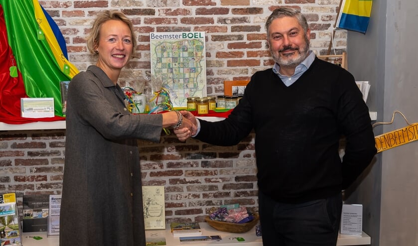 Daniëlle Woudstra en Moncef Beekhof bezegelen de samenwerking. Op de achtergrond de producten uit Beemster die nu een prominente plek hebben in de VVV-winkel.