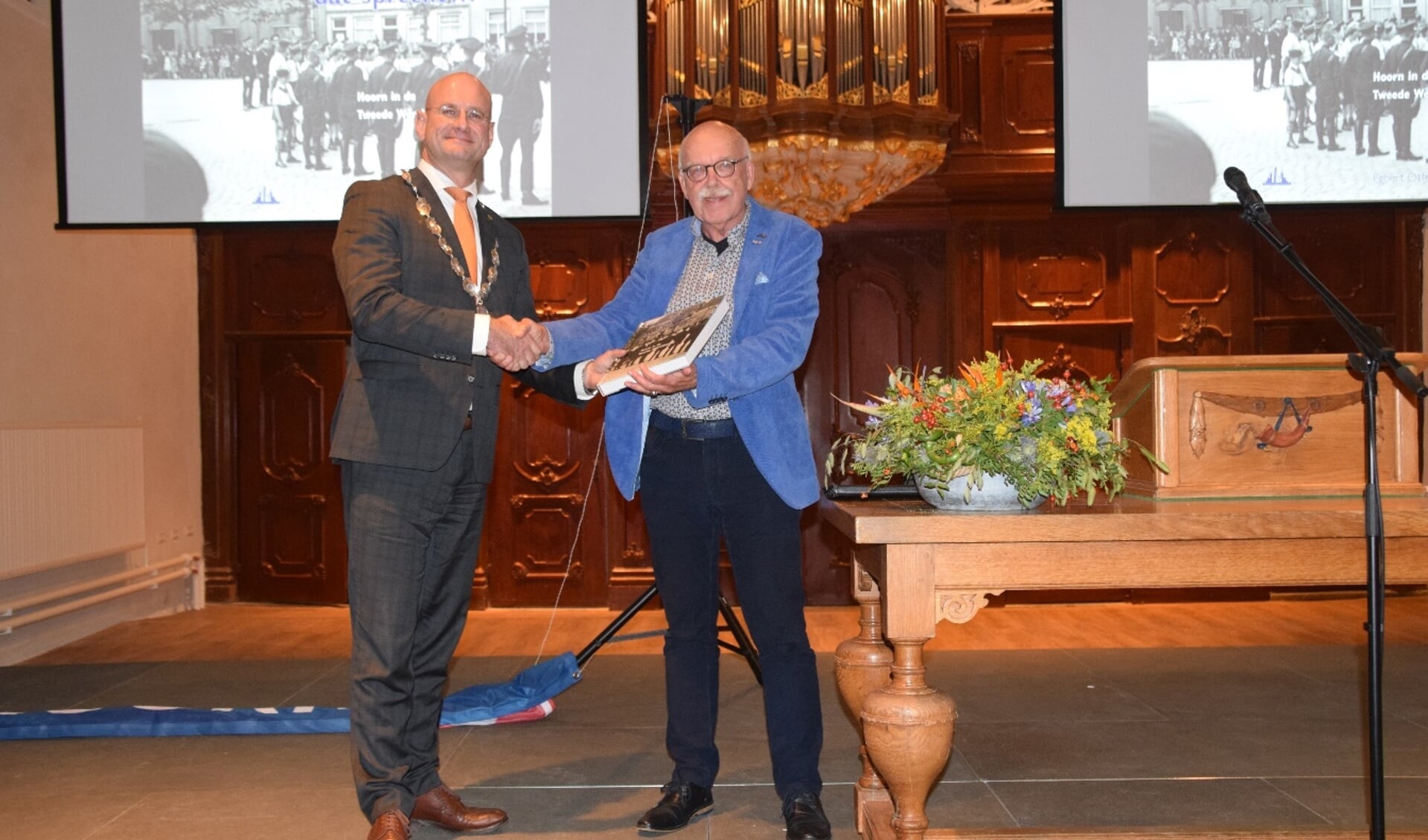 De auteur, Egbert Ottens, overhandigt het eerste boek aan burgemeester Jan Nieuwenburg.