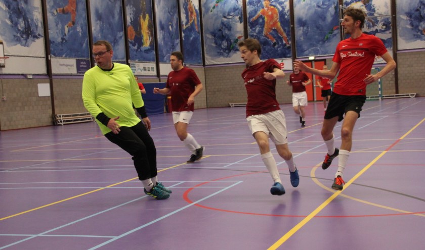 Een speler van Tips Thailand (in helder rood shirt) verschalkt de doelman van Damclub SNA.