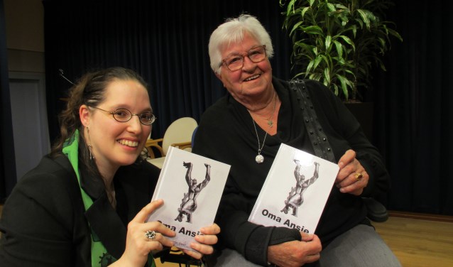 Ans Noordermeer-Peters neemt uit handen van haar kleinkind én schrijfster Geertje Owel het boek 'Oma Ansie' in ontvangst.