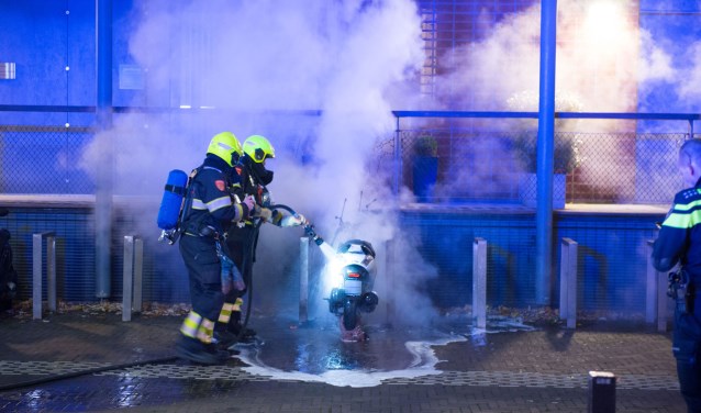 Brandweermannen blussen de brandende scooter.