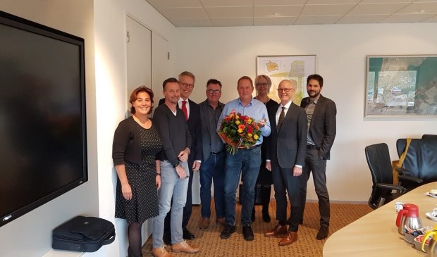 Dirk Groot, met bloemen, temidden van het college.