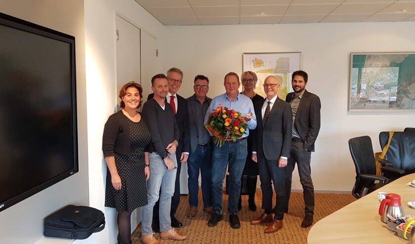 Dirk Groot, met bloemen, temidden van het college.