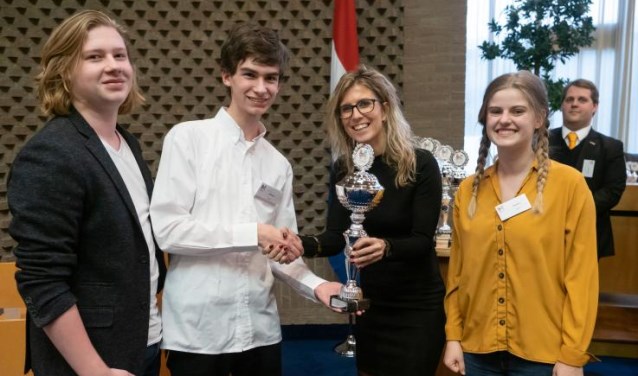 De drie finalisten van het Kaj Munk College ontvangen de beker van hockeykampioen Lisanne de Roever.
